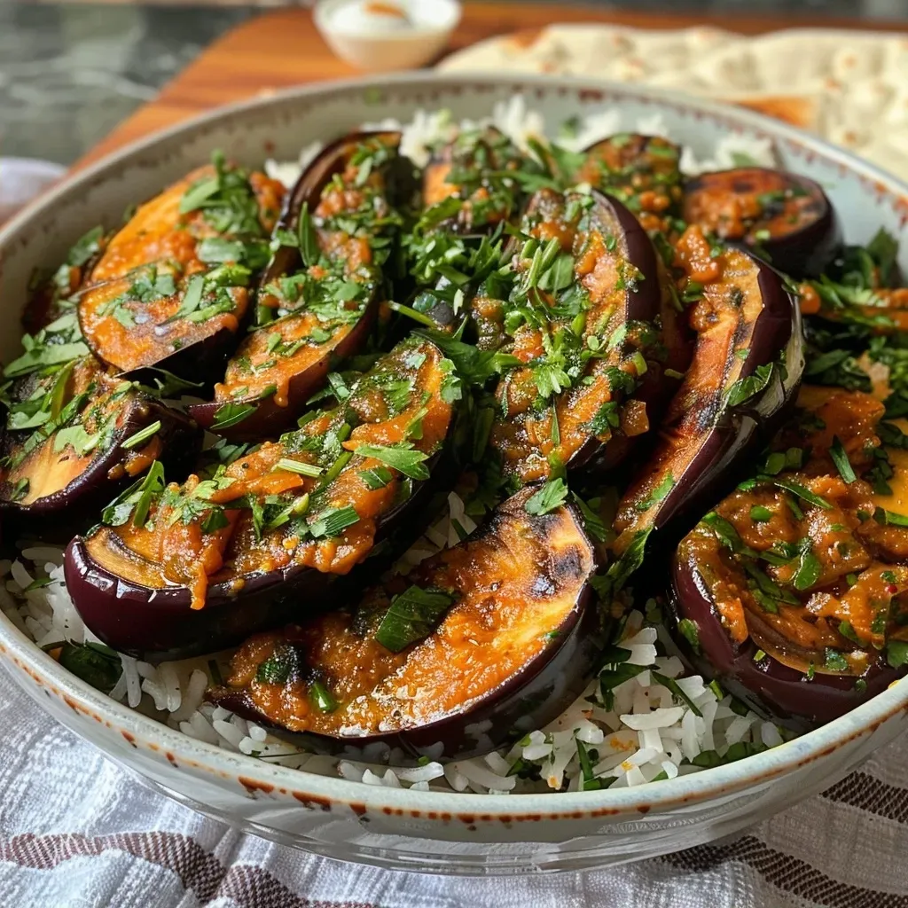 A beautifully plated dish featuring lush aubergines in a rich tamarind sauce, alongside baked halloumi and colorful saffron rice.