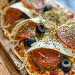 A close-up view of baked pizza wraps filled with cheese, pepperoni, and vegetables.