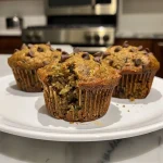 Close-up side view of freshly baked zucchini muffins on a plate.