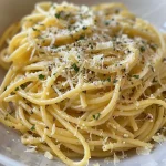 Close-up of spaghetti coated in lemon-parmesan sauce with a sprinkle of basil.