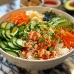 Close-up view of a colorful sushi bowl with diced imitation crab, sliced cucumbers, shredded carrots, and avocado.