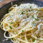 A close-up view of Zitronen Parmesan Spaghetti adorned with green asparagus on a plate.